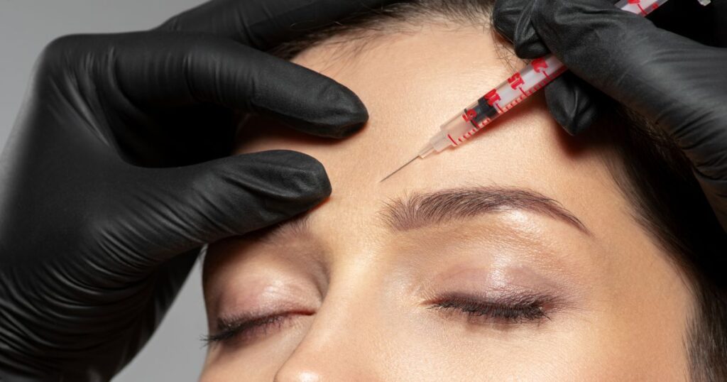 A person receiving a Botox injection in the forehead, administered by hands in black gloves, highlights how it works to smooth wrinkles effectively.