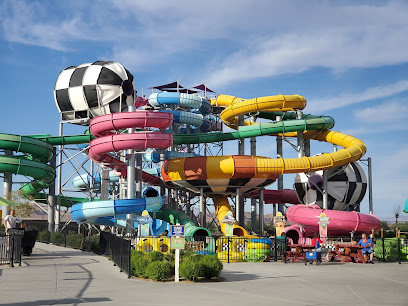 Colorful water slides with twists and turns at an outdoor water park, set against a blue sky with scattered clouds.