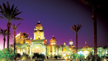 Sunset Station Hotel and Casino is illuminated at night, with palm trees and a deep purple sky in the background.